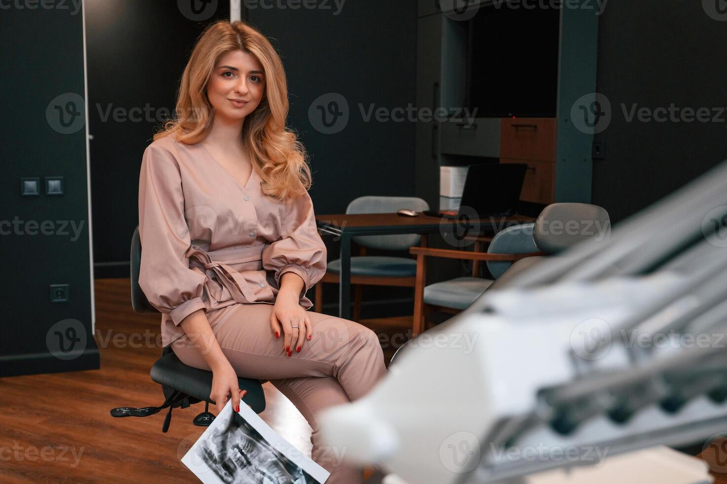 Holding x-ray of teeth. Beautiful young, female doctor, is indoors in the cabinet photo