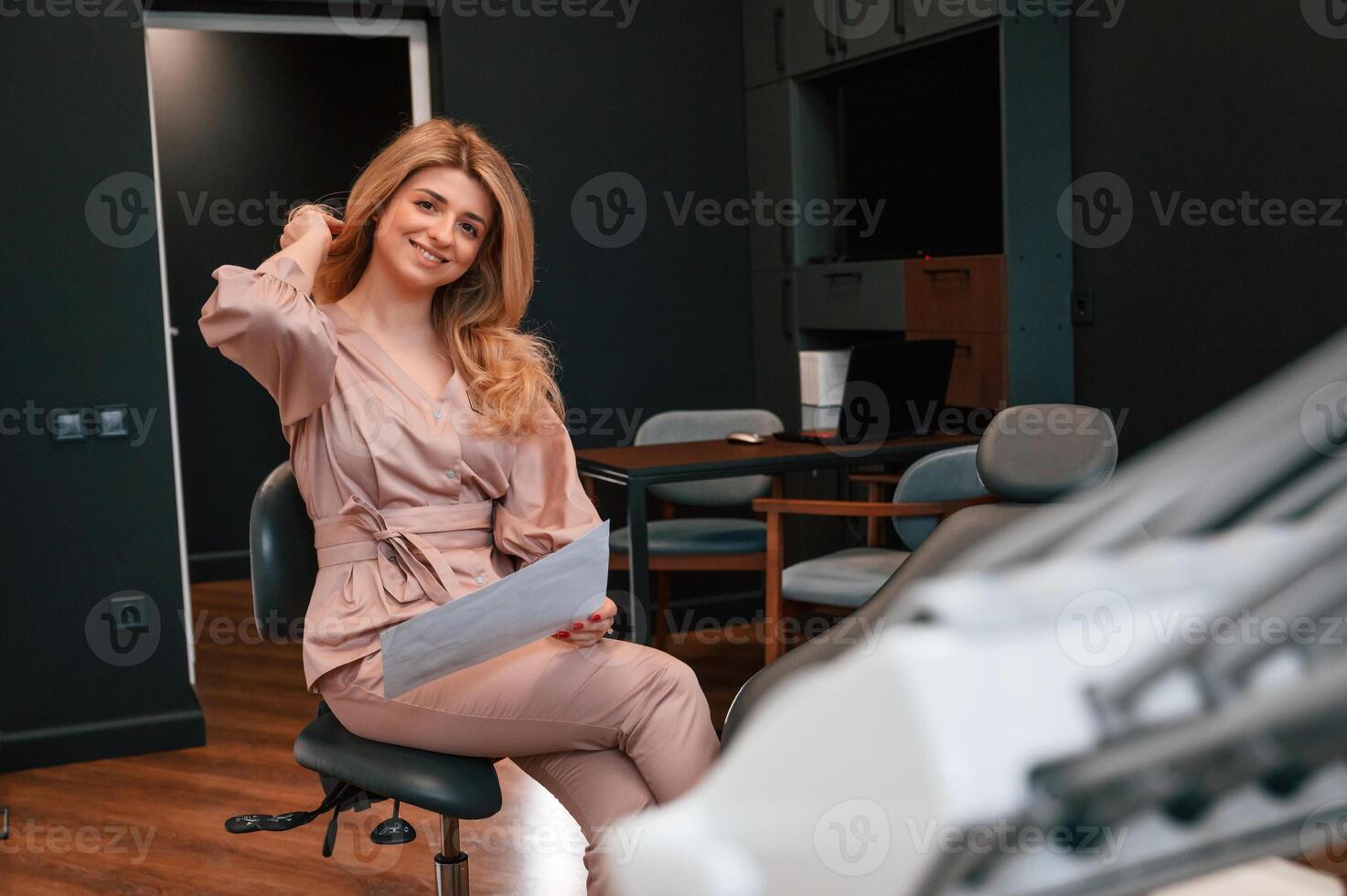 Sitting and holding document., Beautiful ,young female doctor is indoors in the cabinet photo