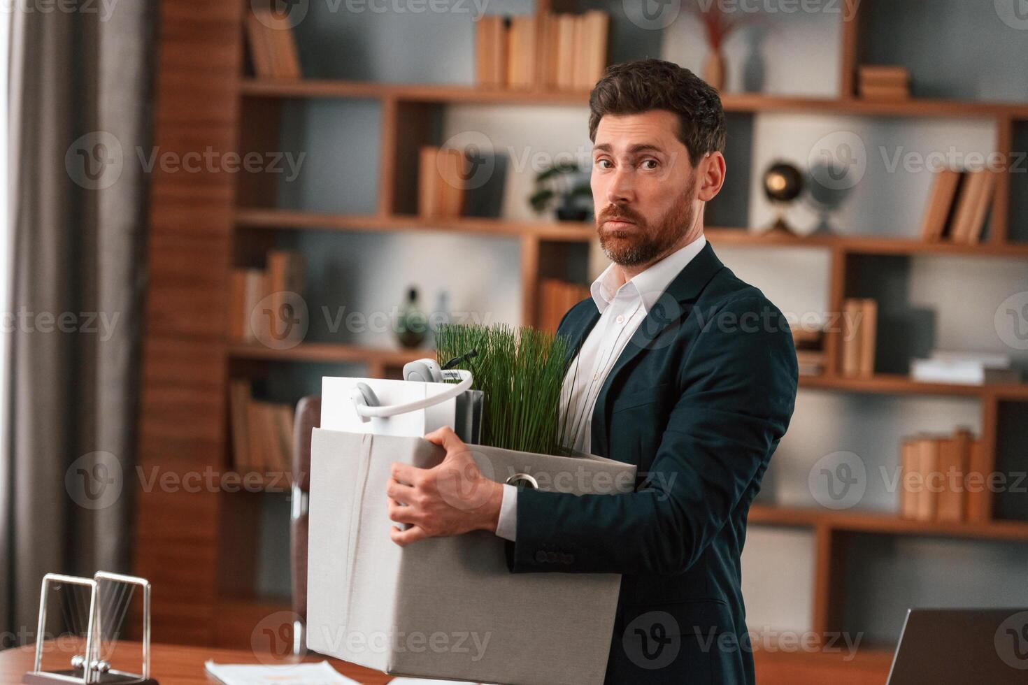 With a box of stuff in it. .Businessman in formal clothes is working indoors photo