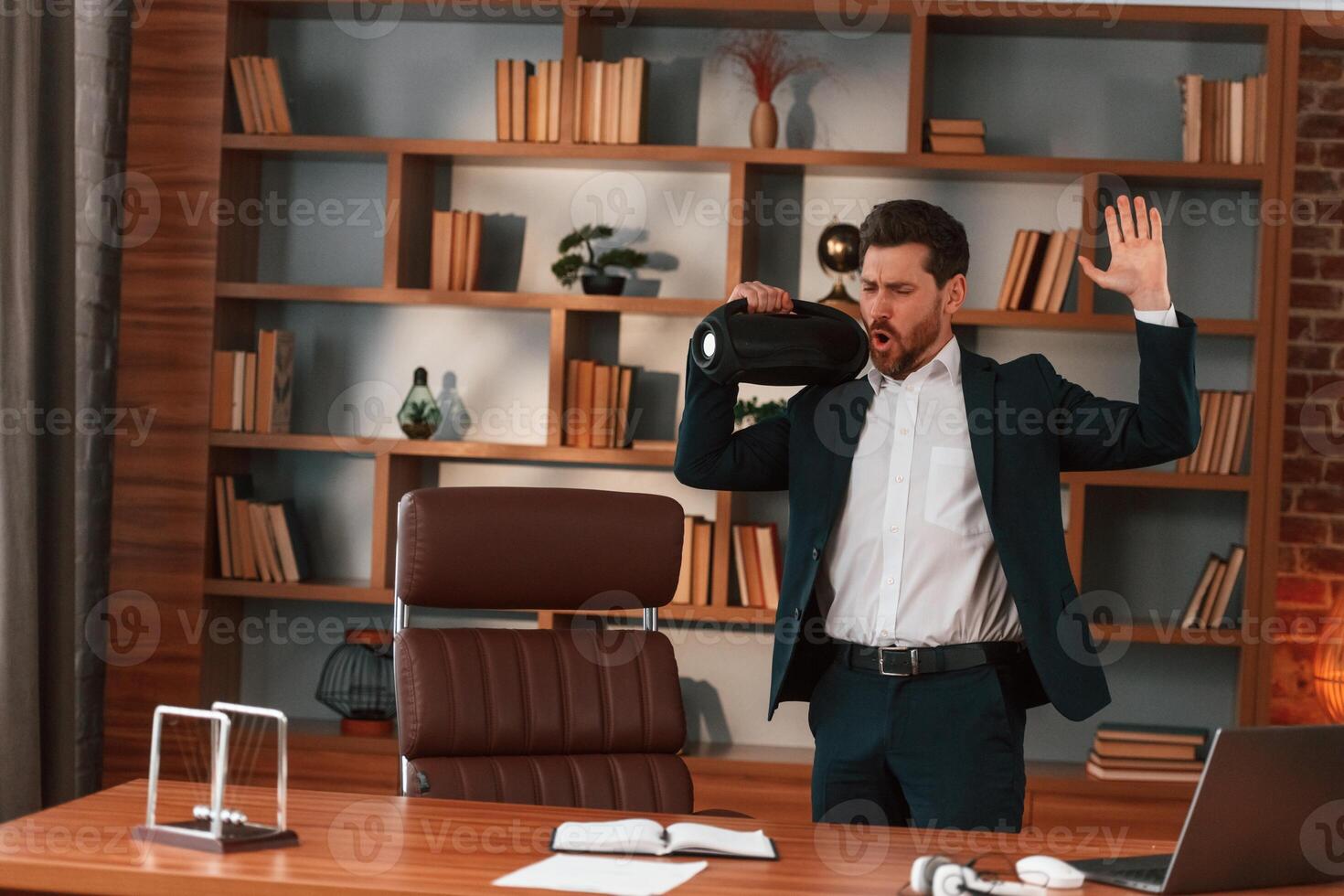Holding speaker and enjoying the, music. Businessman in formal clothes is working indoors photo