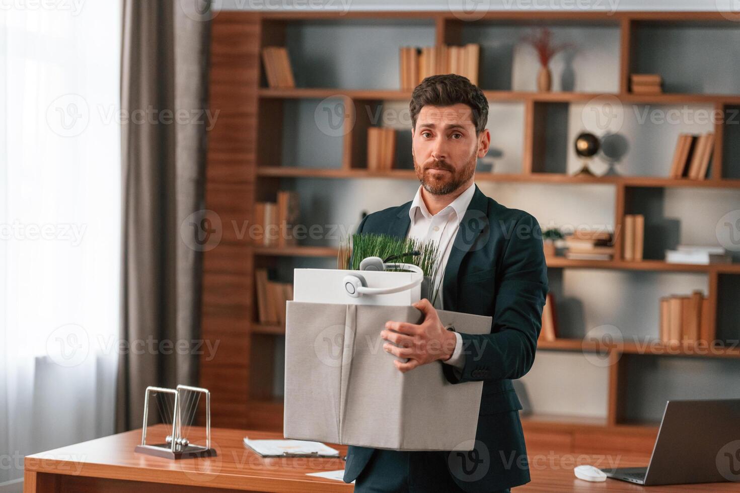 With a box, of stuff in it. Businessman in formal clothes is working indoors photo