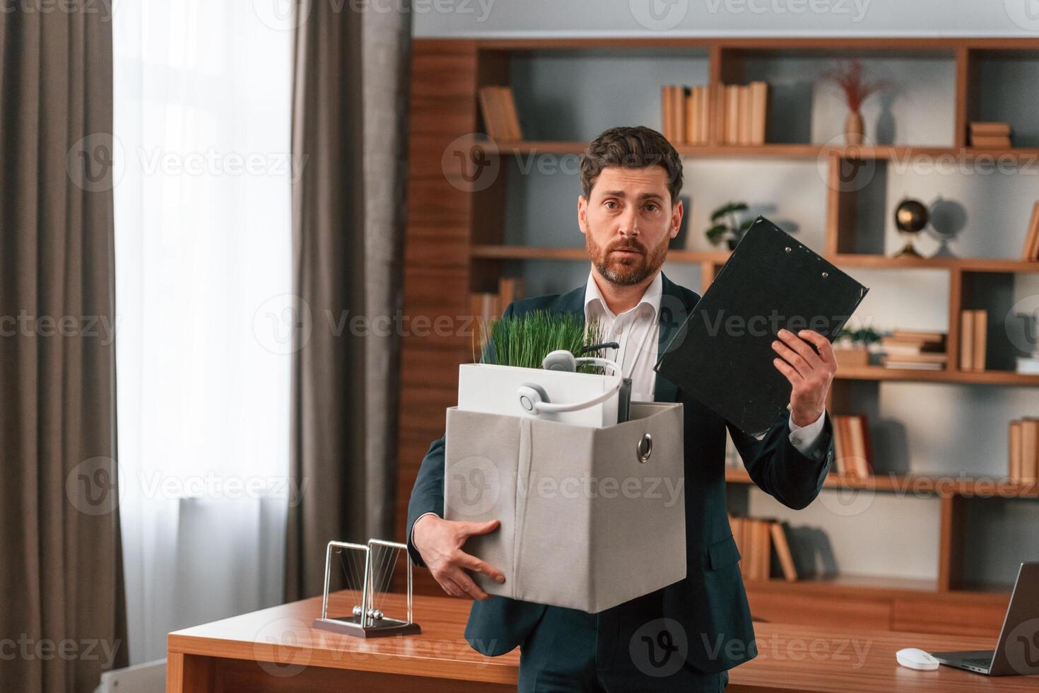 With a box of stuff ,in it. Businessman in formal clothes is working indoors photo