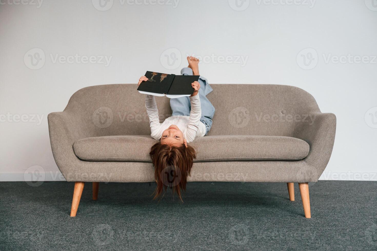 Little girl is ,lying down on the sofa at home. photo