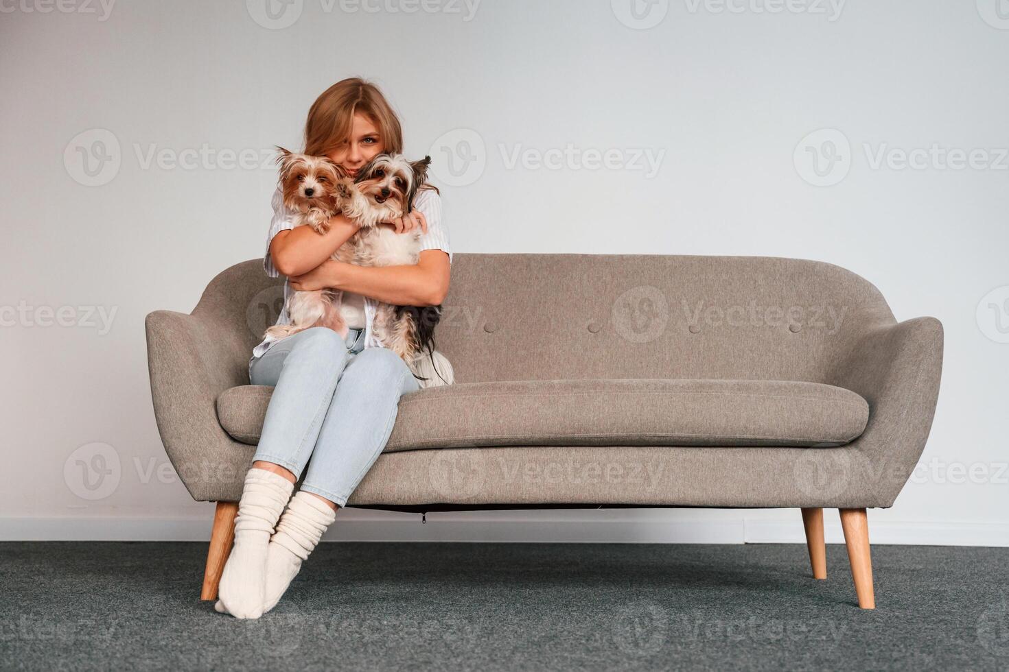 Conception of care and love.. Woman is sitting on a sofa with two cute dogs photo
