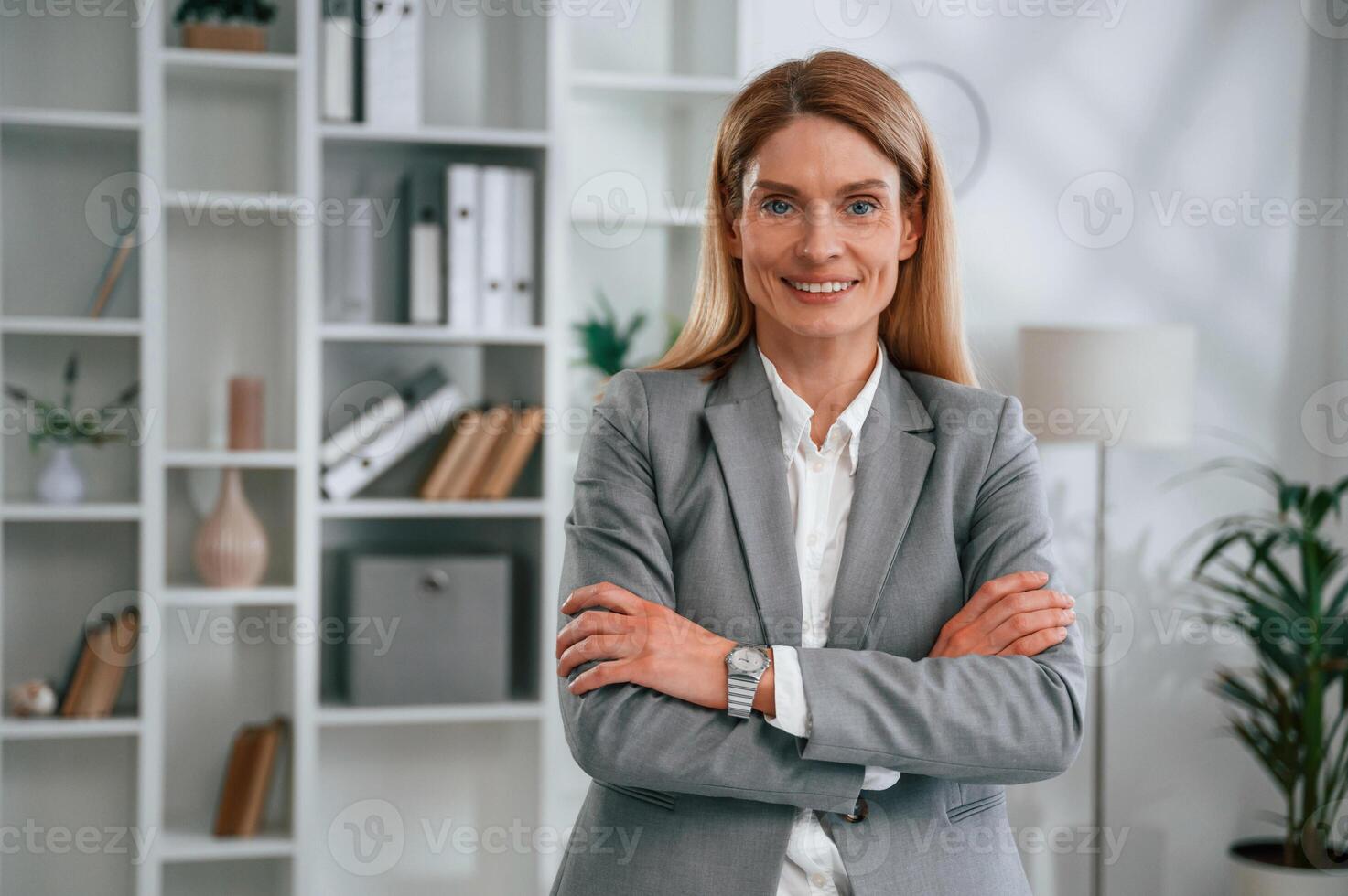 Standing with, arms crossed. Woman in business formal clothes is working in office photo