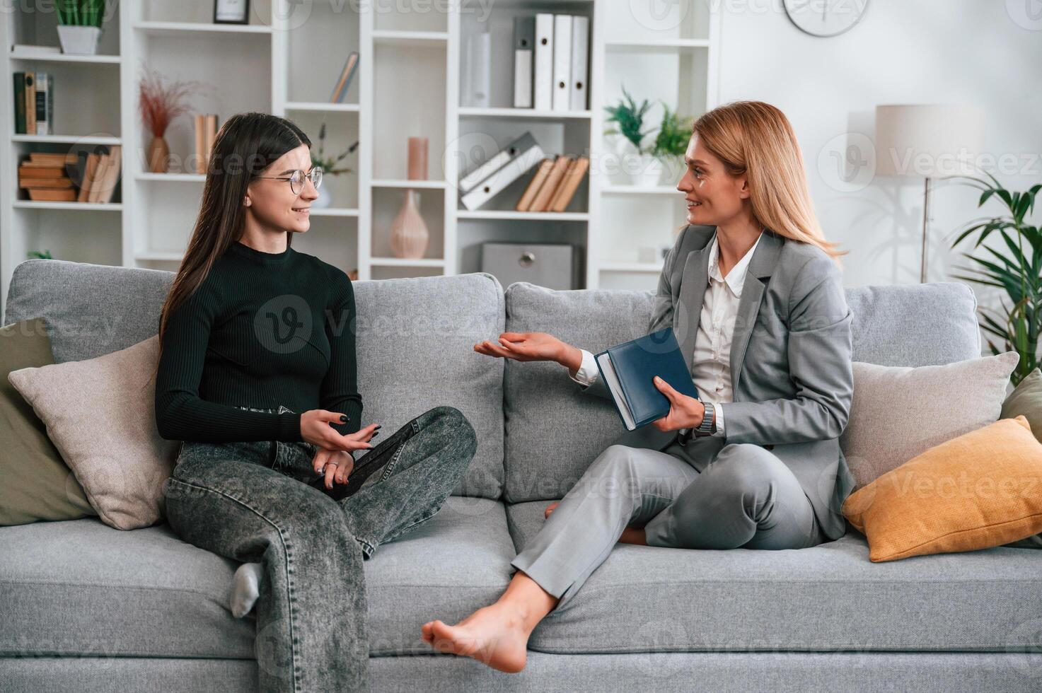 Two women is sitting on the sofa and talking.. Casual and formal clothes photo