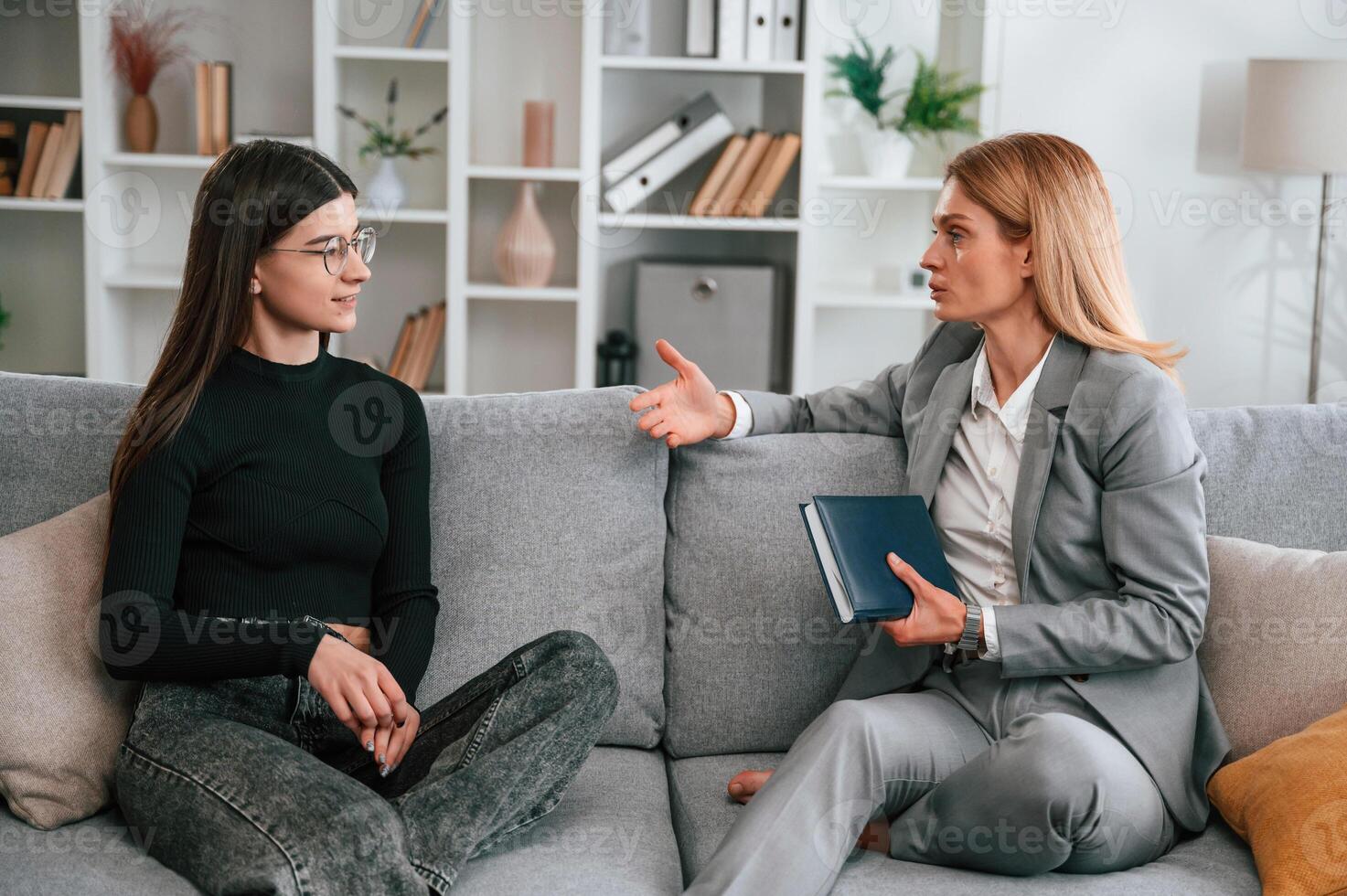 Two ,women is sitting on the sofa and talking. Casual and formal clothes photo