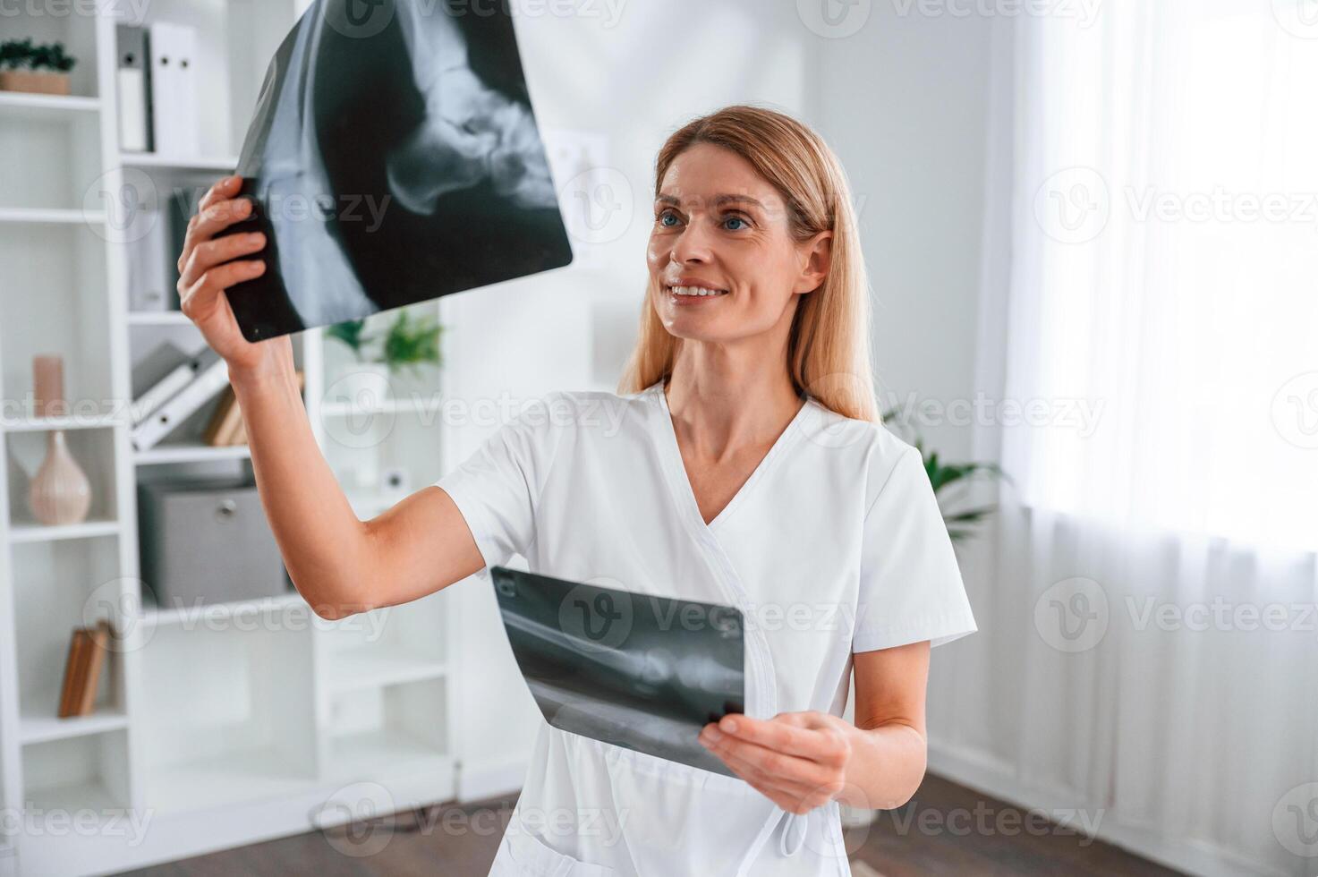 Checking x-ray.. Young female doctor in white coat is indoors photo