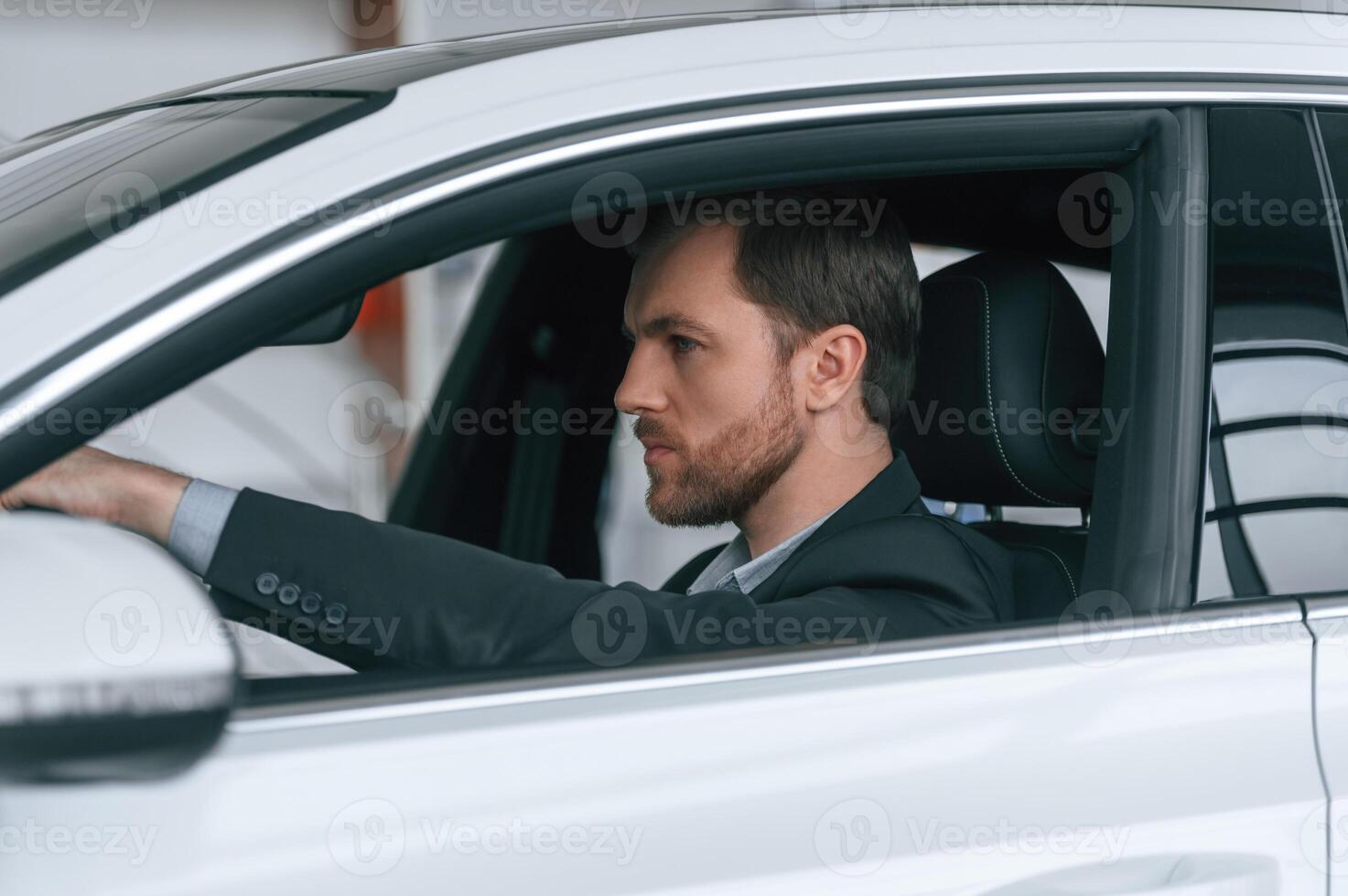 Serious, facial expression. Driving the car. Man in formal business clothes is sitting in the modern automobile photo