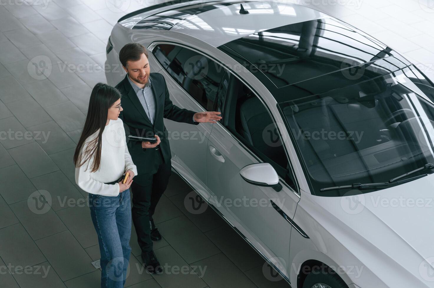 Top,, view. Man is showing the new automobile to the woman customer in the car dealership photo