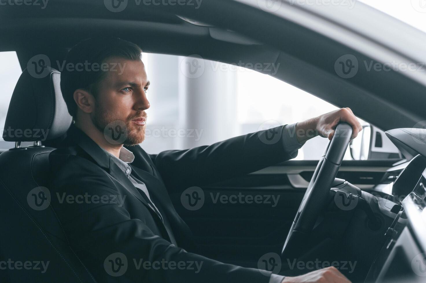 Serious facial expression. Driving the, car. Man in formal business clothes is sitting in the modern automobile photo