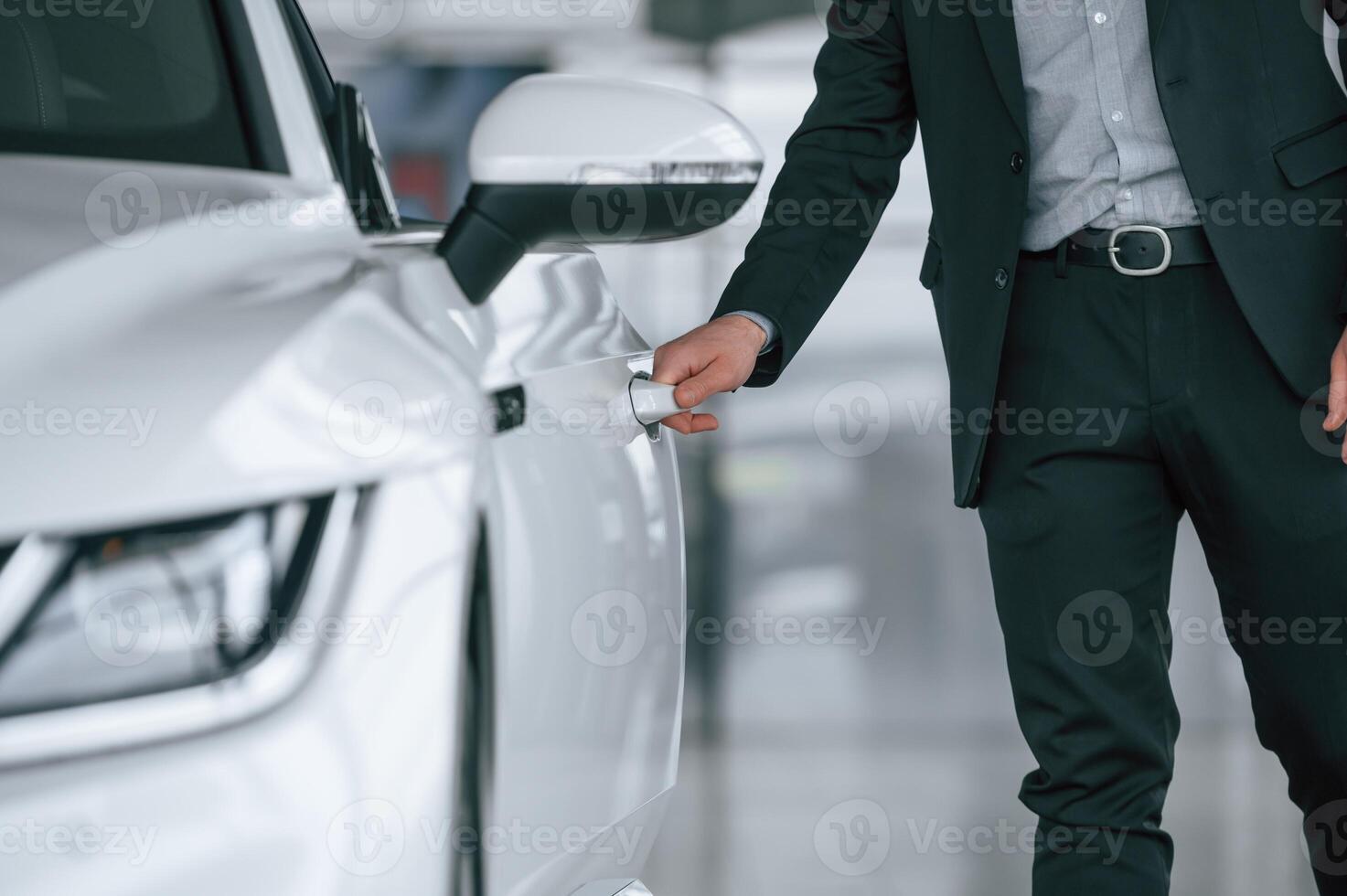 Close, up, view of man in suit that is opening the door of the new white colored automobile photo