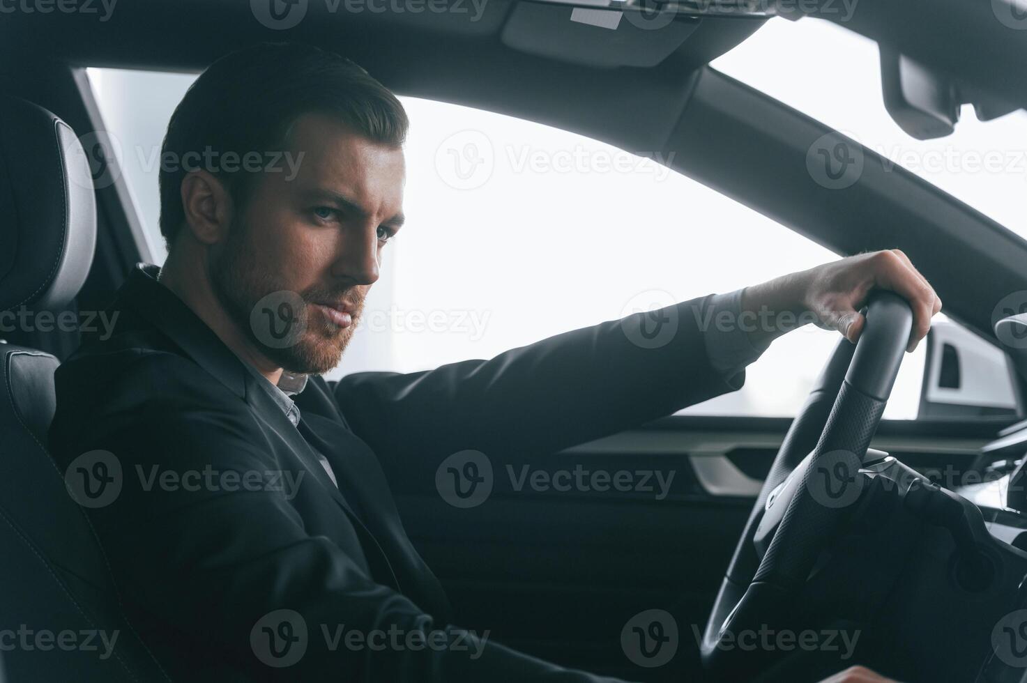 Serious facial expression.. Driving the car. Man in formal business clothes is sitting in the modern automobile photo