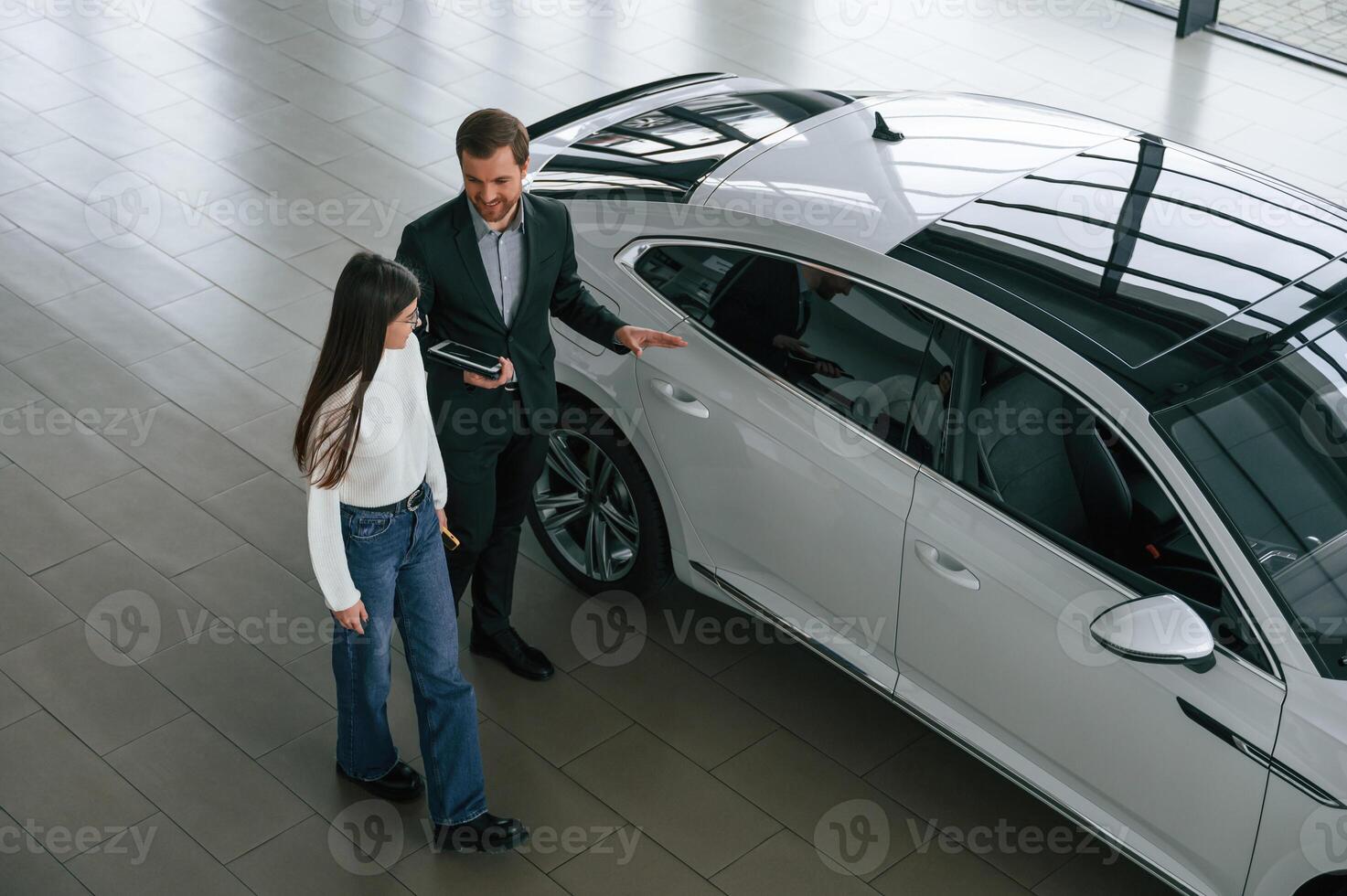 Talking, holding ,tablet. Man is showing the new automobile to the woman customer in the car dealership photo