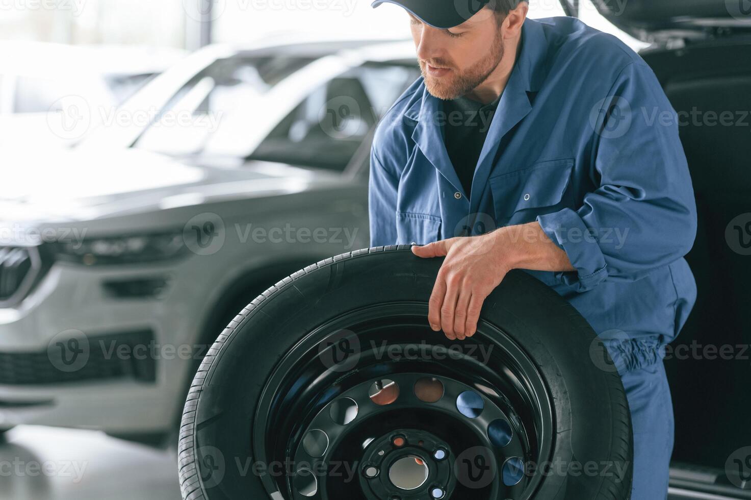 Tire replacement, concept. Man in blue uniform is working in the car service photo
