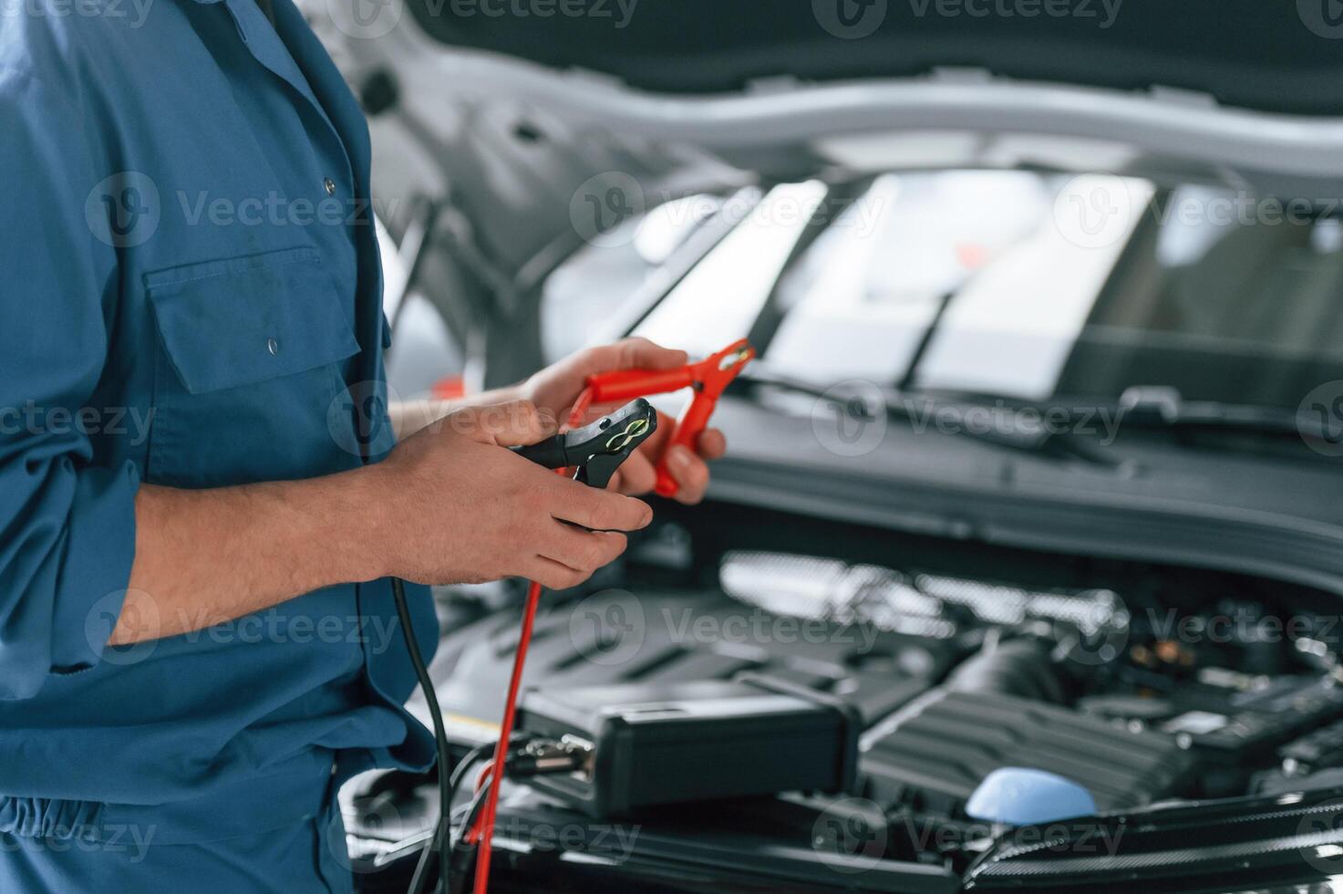 Testing,, breakage by using electrical terminals. Man in blue uniform is working in the car service photo