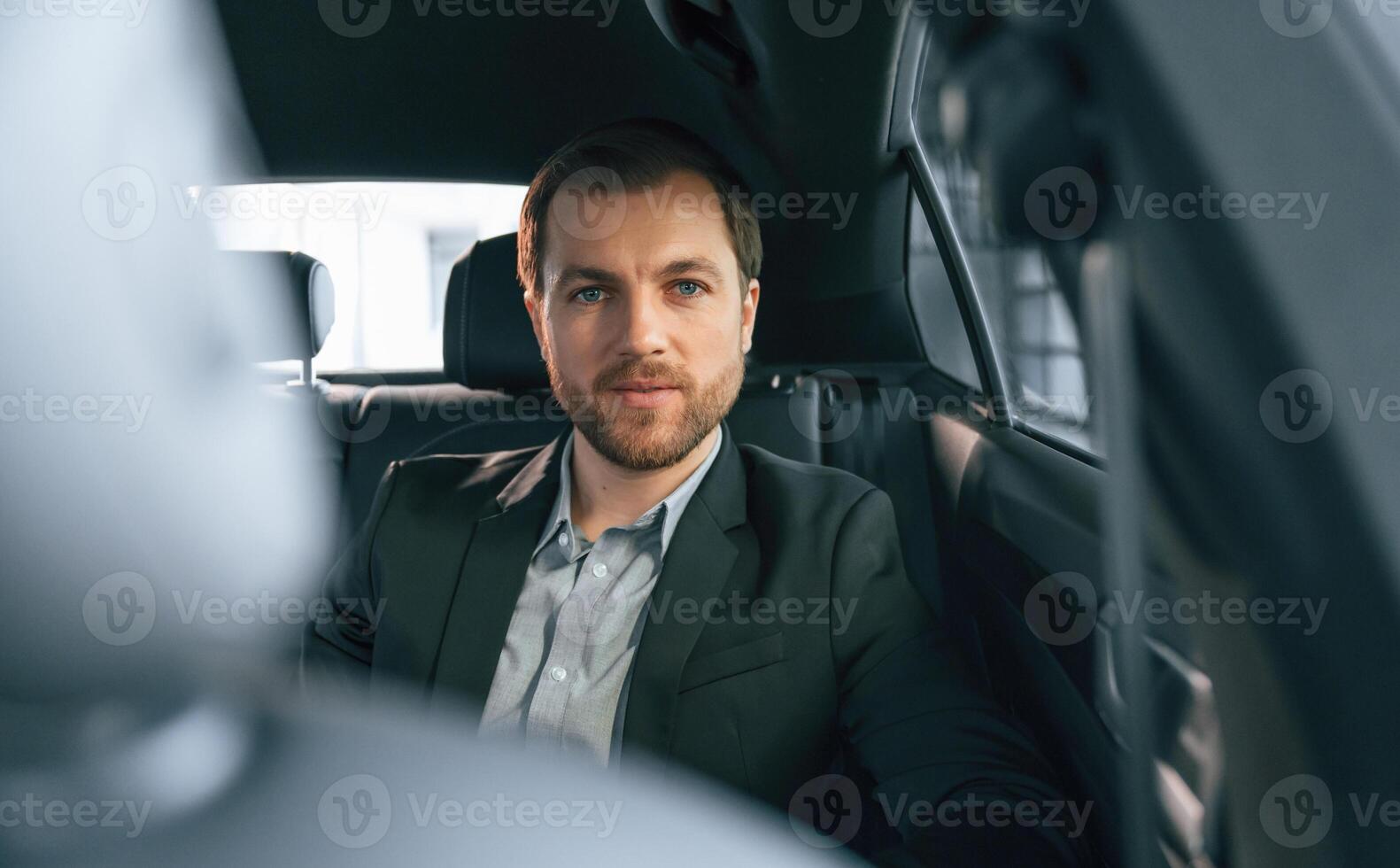 In comfortable, modern automobile. Man in formal business clothes photo