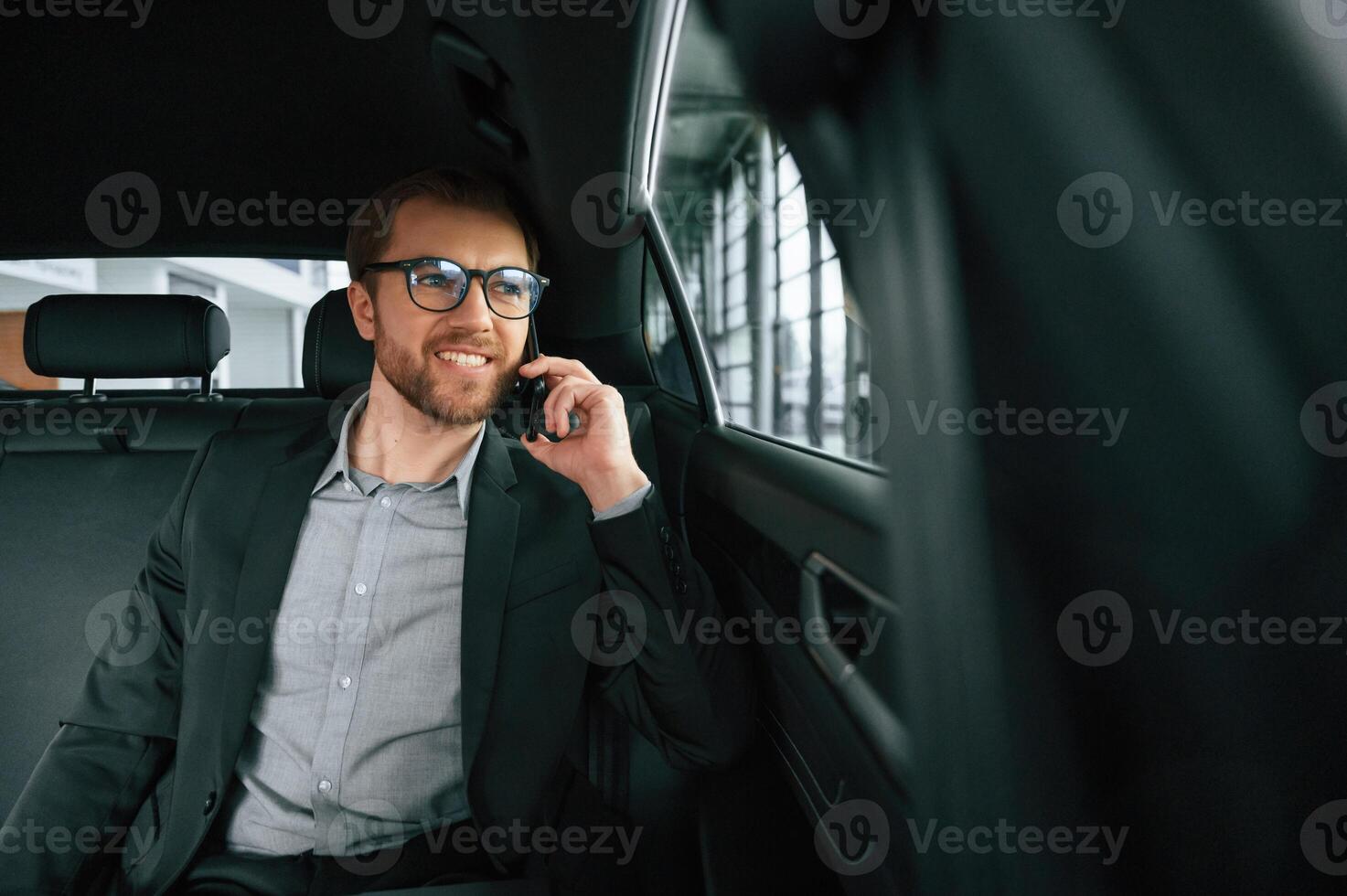 Talking by phone. Man in formal business clothes ,is sitting in the modern automobile photo