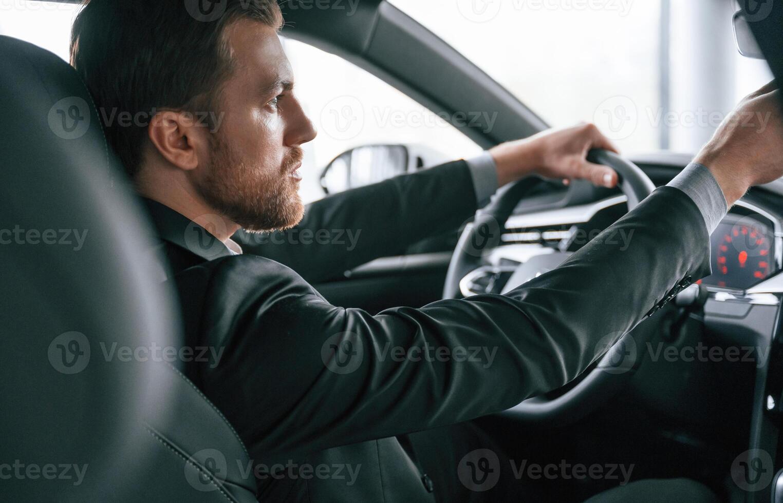 Driving the, car. Man in formal business clothes is sitting in the modern automobile photo