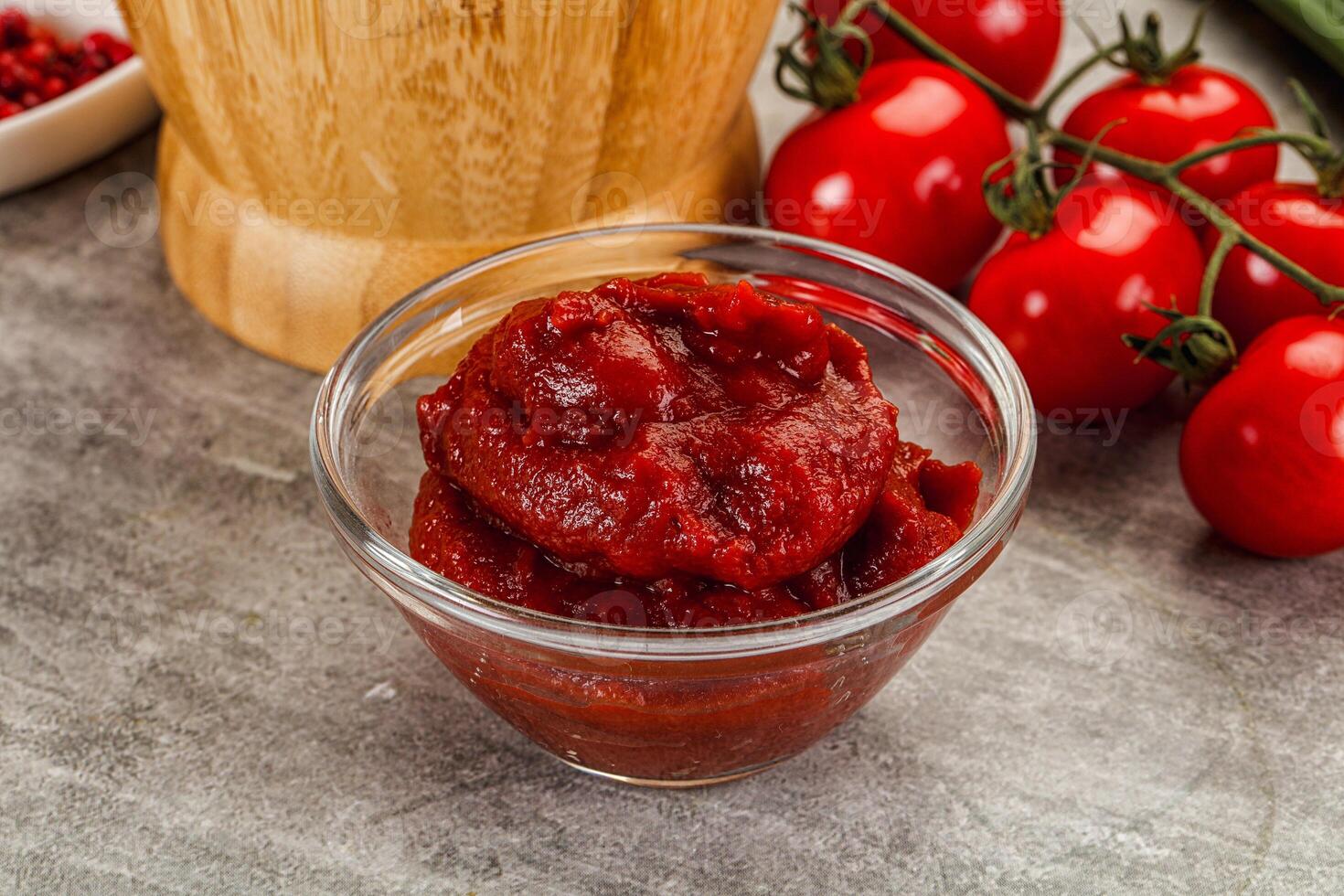 A bowl of tomato sauce next to a knife and a bowl of tomatoes photo