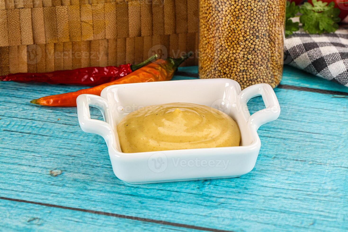 A bowl of mustard and a basket of peppers photo