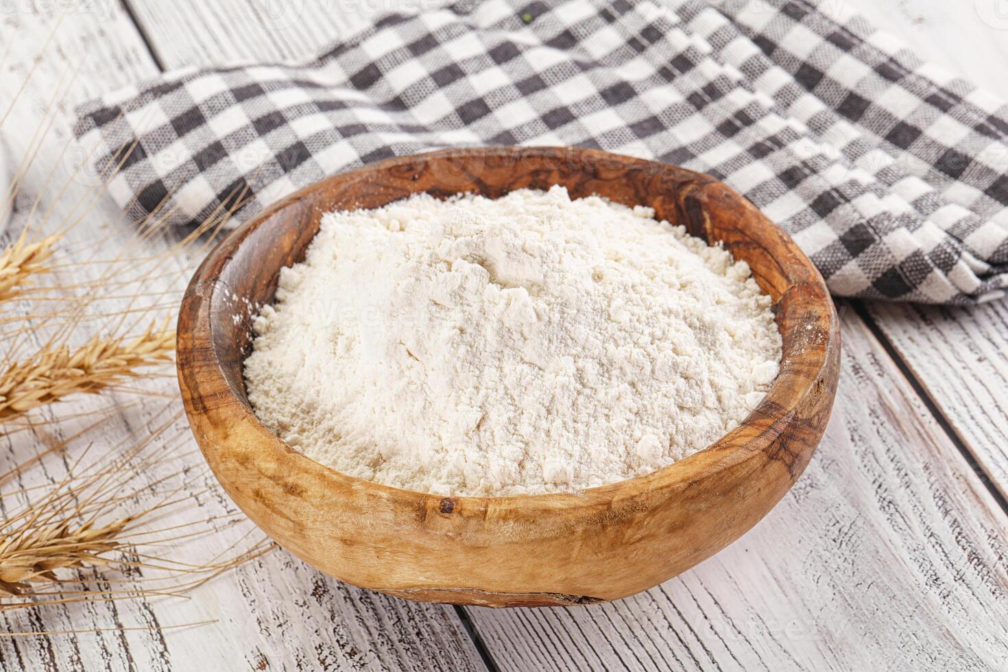 Flour in a wooden bowl on a white wooden table photo