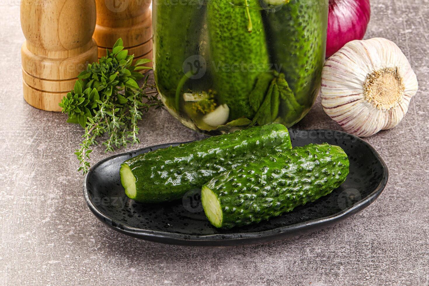 A jar of pickles and a bowl of onions and garlic photo