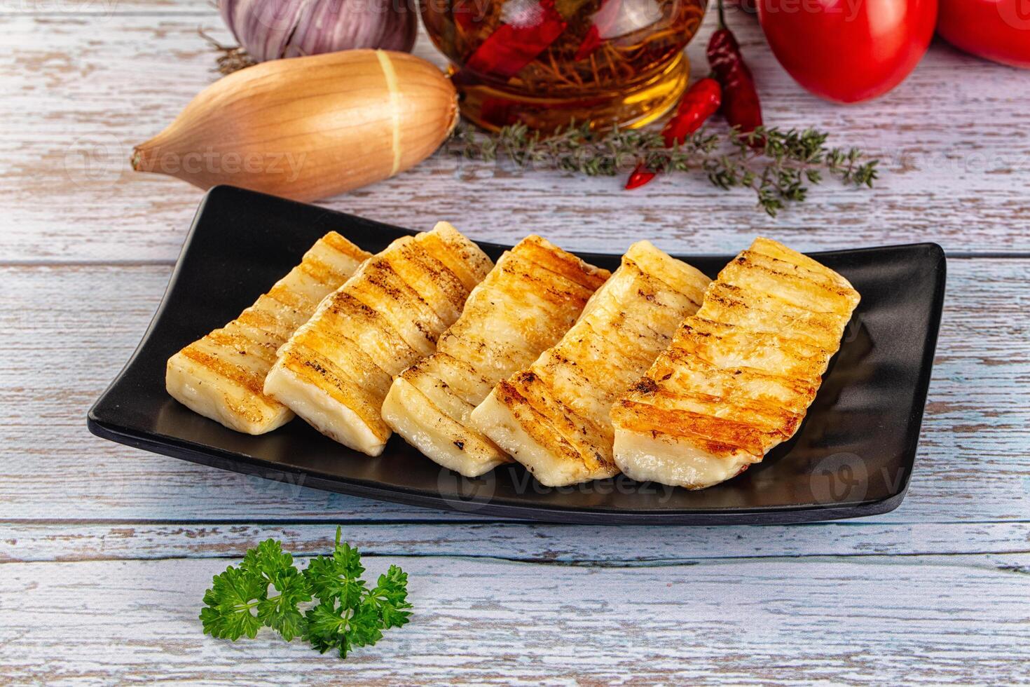 Grilled tofu on a black plate with vegetables and spices photo