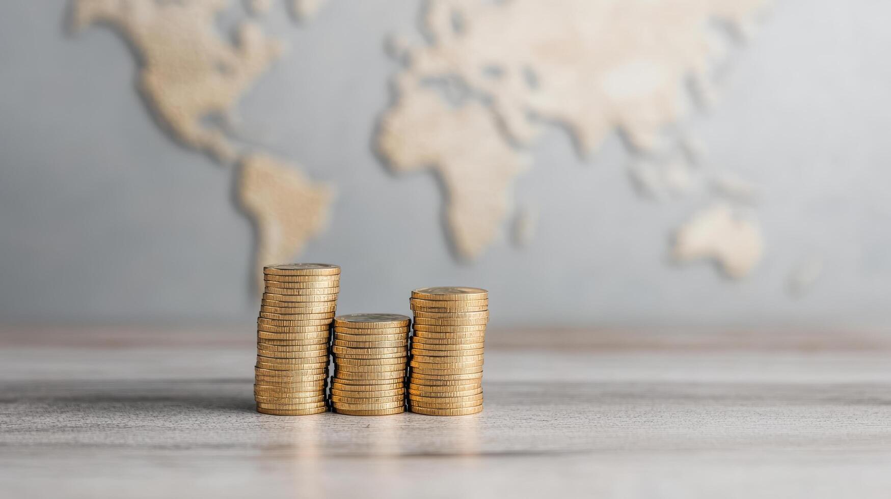 Stacks of coins represent financial growth against world map backdrop, symbolizing global photo