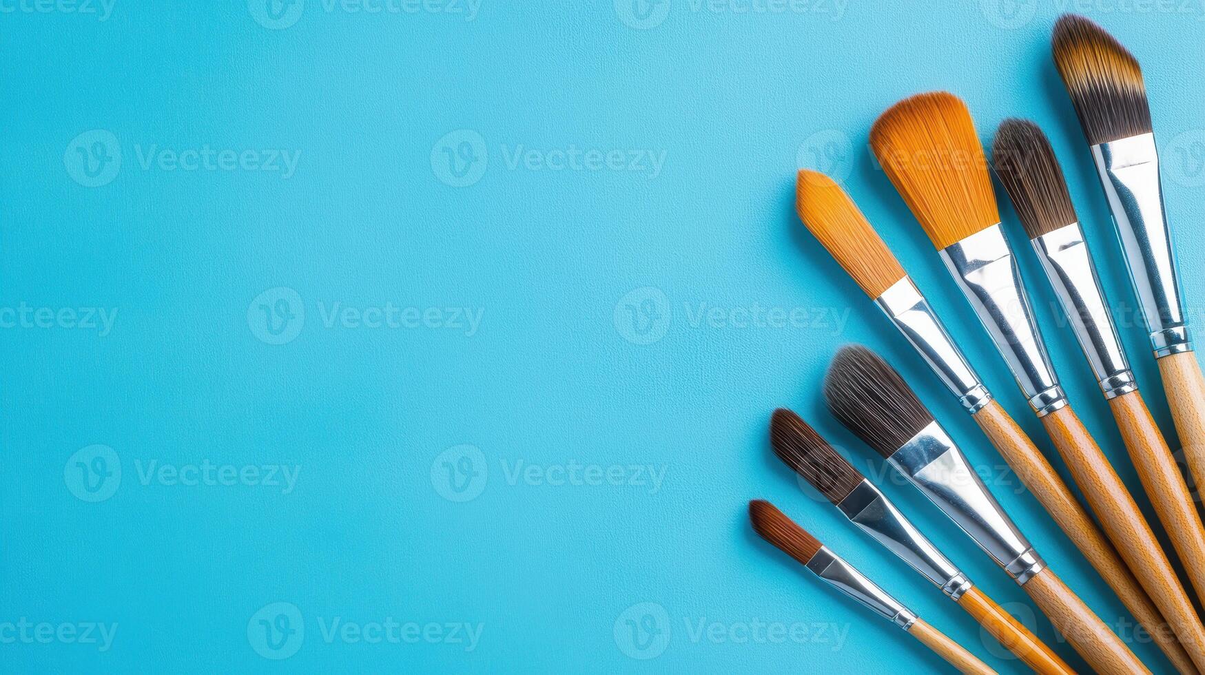 Assorted paintbrushes arranged on blue canvas ready for artistic expression and creative projects photo