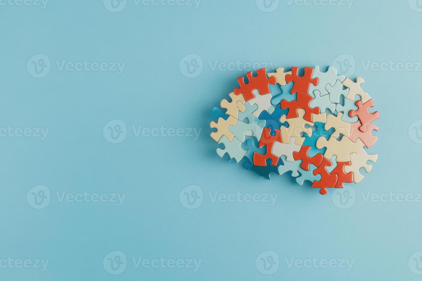 Colorful jigsaw puzzle pieces forming a brain shape on a solid blue background photo