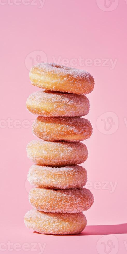 Stack of sugary donuts arranged in a tall tower against a pastel pink background photo