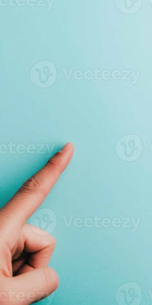 Close up of a pointing finger against a soft turquoise background creating a minimalist and modern aesthetic photo