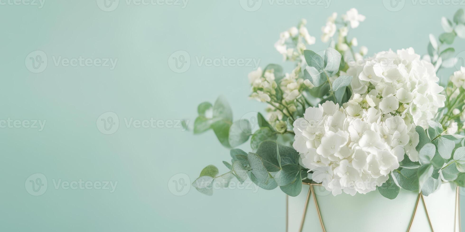 Elegant white hydrangeas and eucalyptus arrangement in vase against soft green background photo