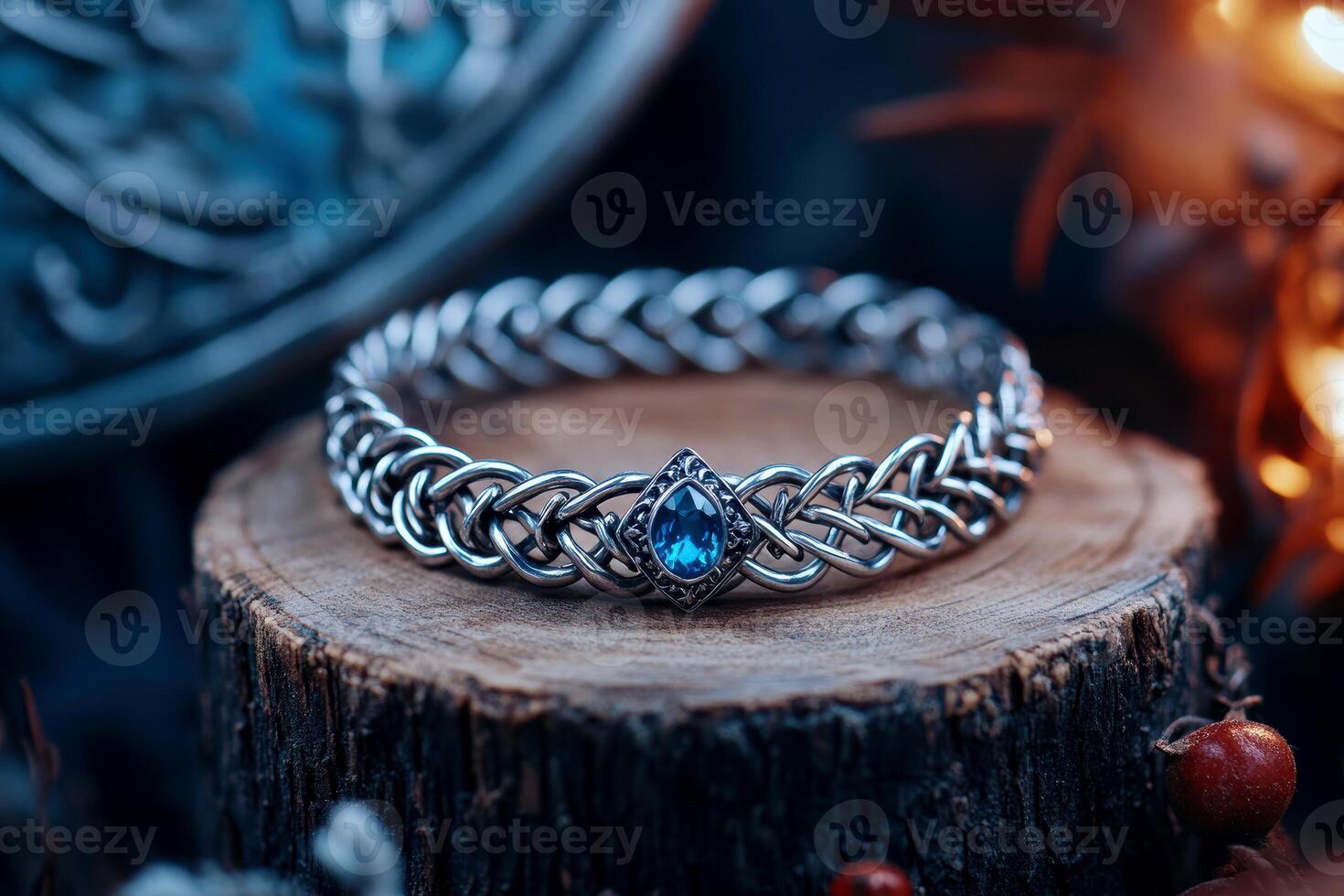 Elegant silver bracelet with intricate woven design and blue gemstone centerpiece displayed on rustic wood with atmospheric lighting, photo