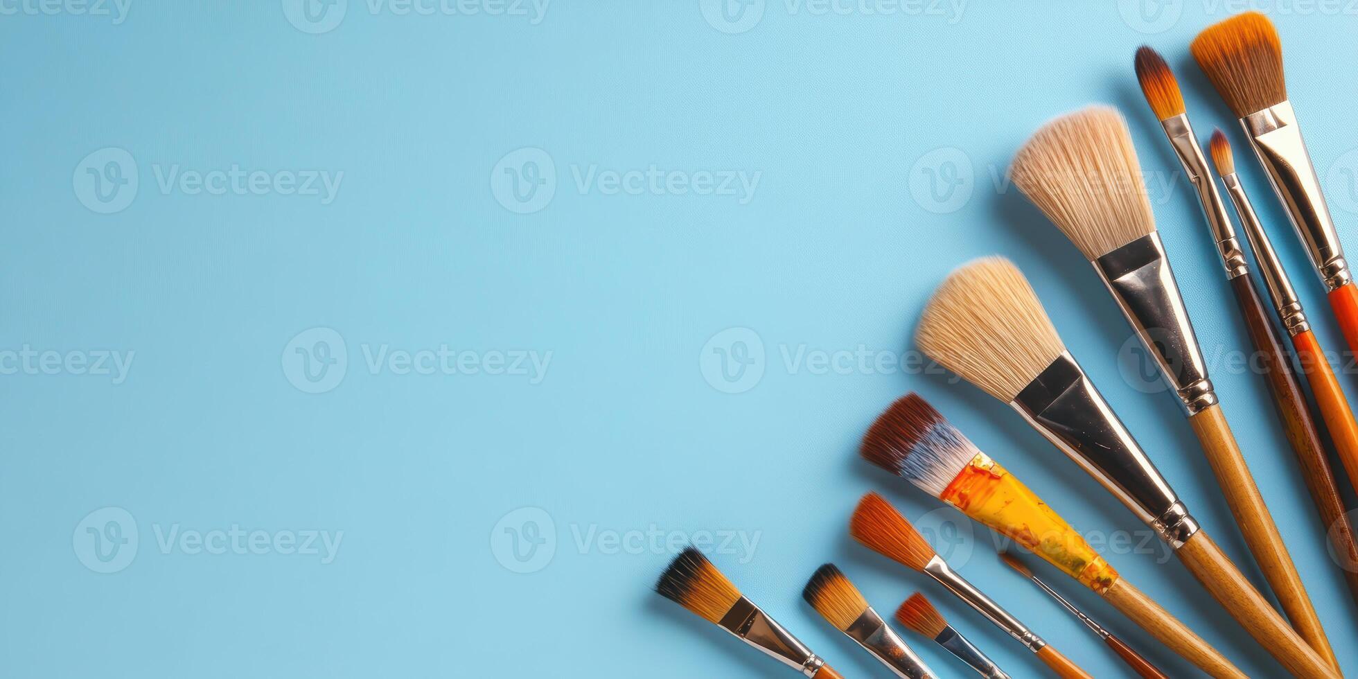 Collection of artist paintbrushes arranged in a fan shape on a blue background photo