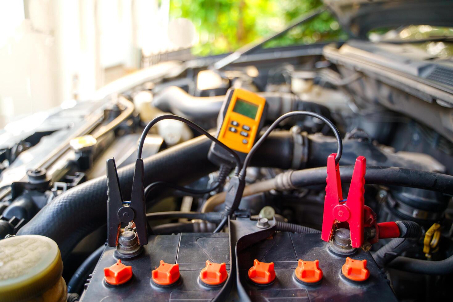 Close-up of Black and red charging cable clamps on battery terminals for charging a car charger cable and jump-starting a dead car battery, The concept of car repair and maintenance at home photo