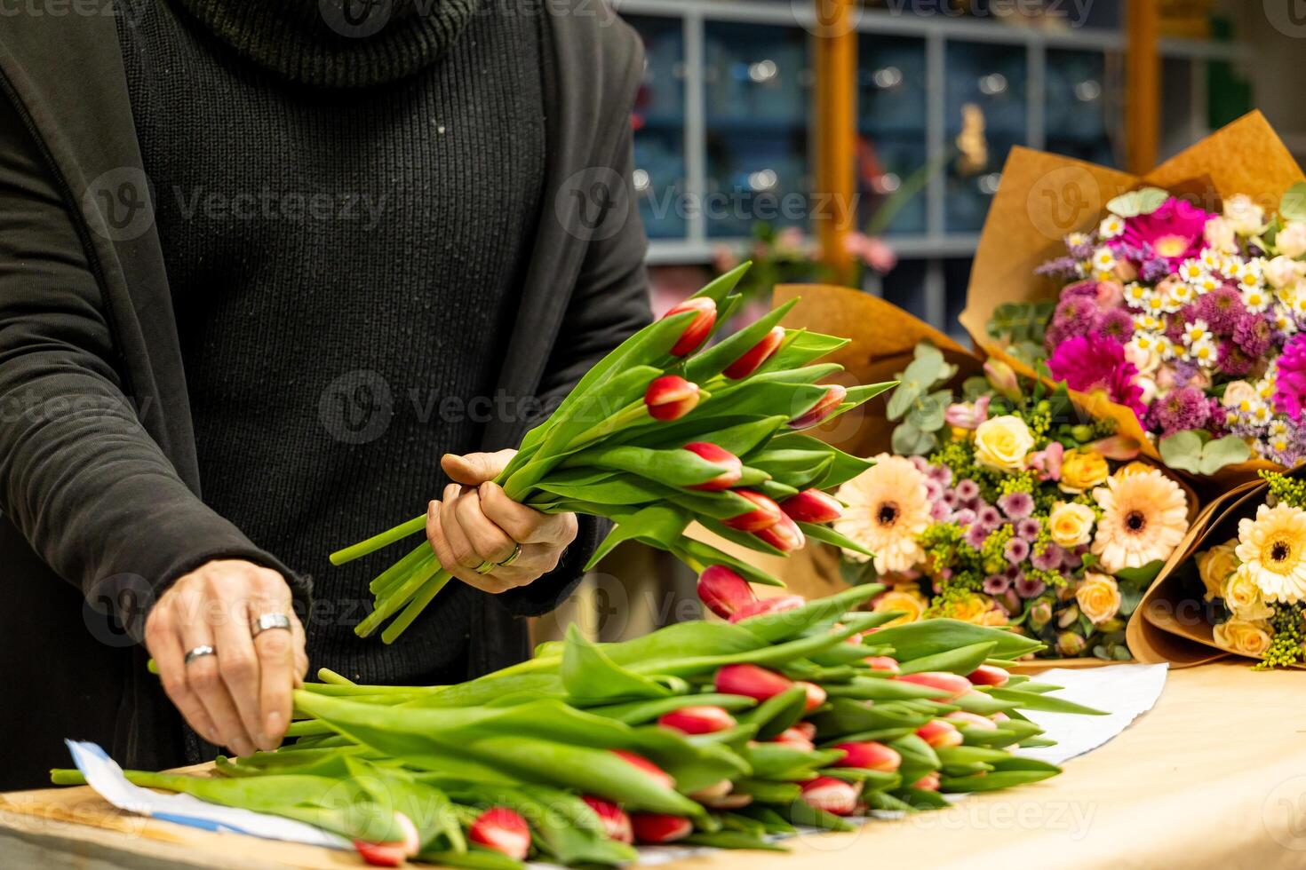 Florist arranging red and white tulips for bouquet in flower shop photo
