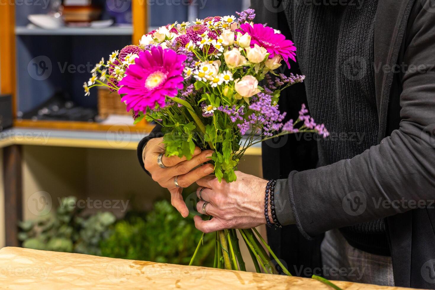Florist arranging bouquet with pink gerberas and white roses in flower shop photo
