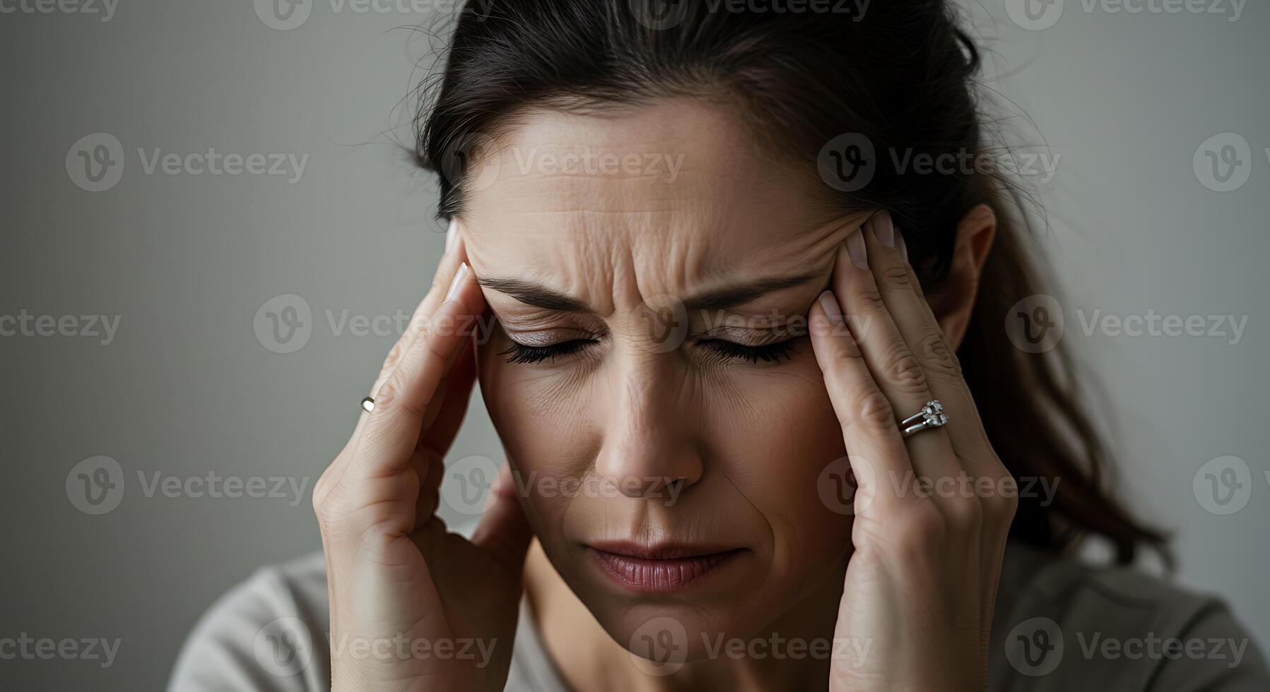 A woman with a headache holding her hands to her head photo
