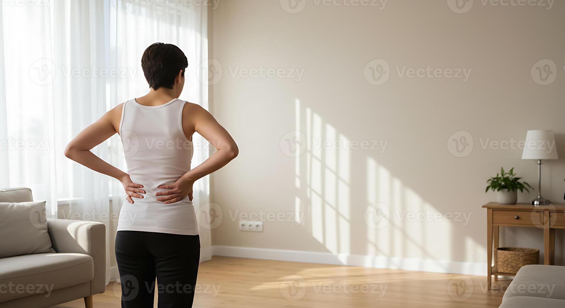 Woman Experiencing Back Pain in a Sunlit Room A Minimalist Scene photo