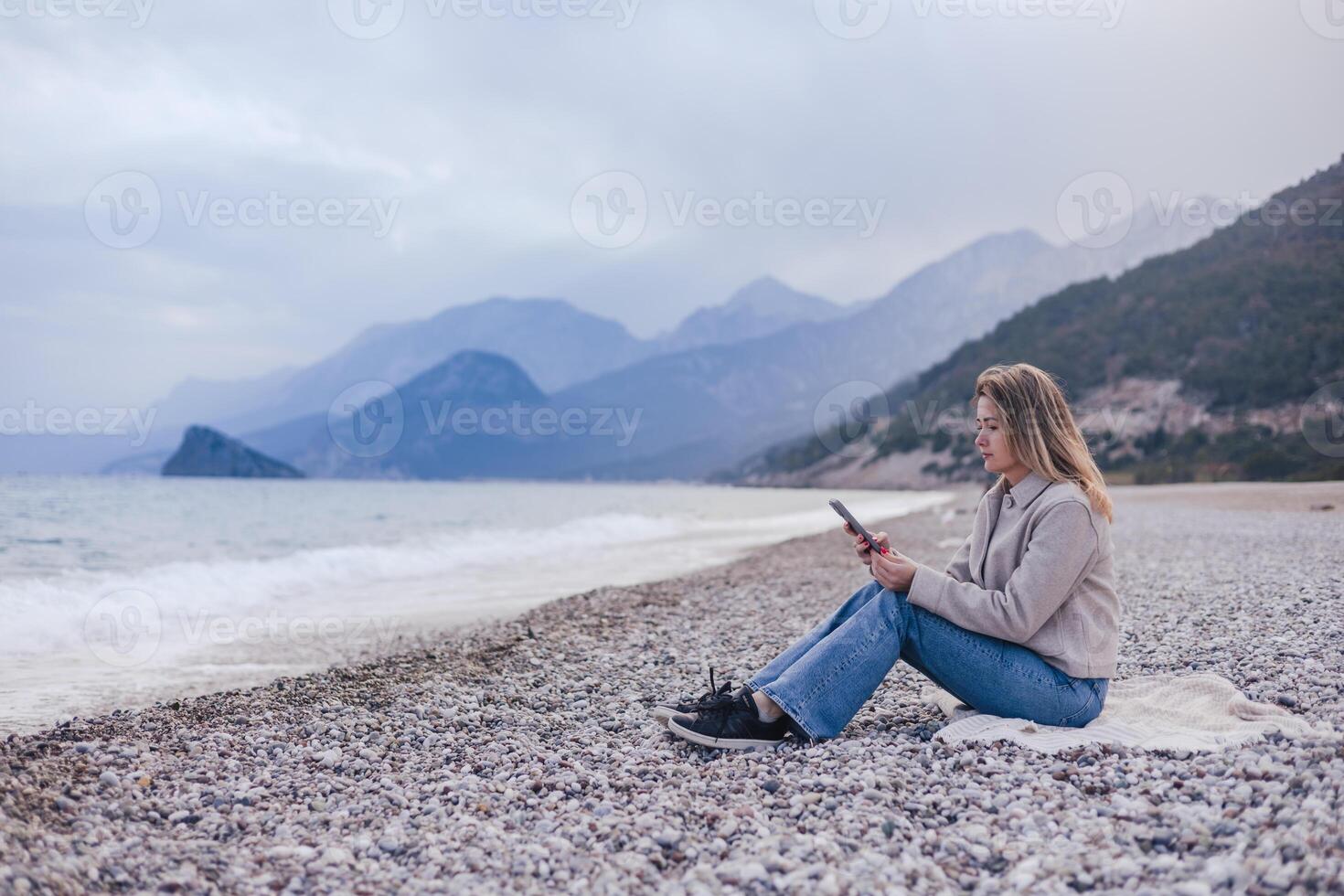 Mother and son enjoy winter beach day with mountain backdrop by the sea photo