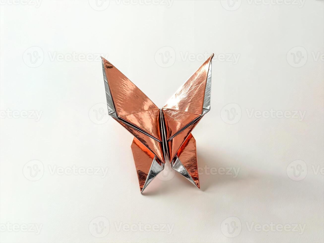 symmetrical origami butterfly crafted from shiny metallic paper in gold and silver tones featuring intricate detailed folds and a sleek modern artistic aesthetic placed on a smooth neutral surface photo