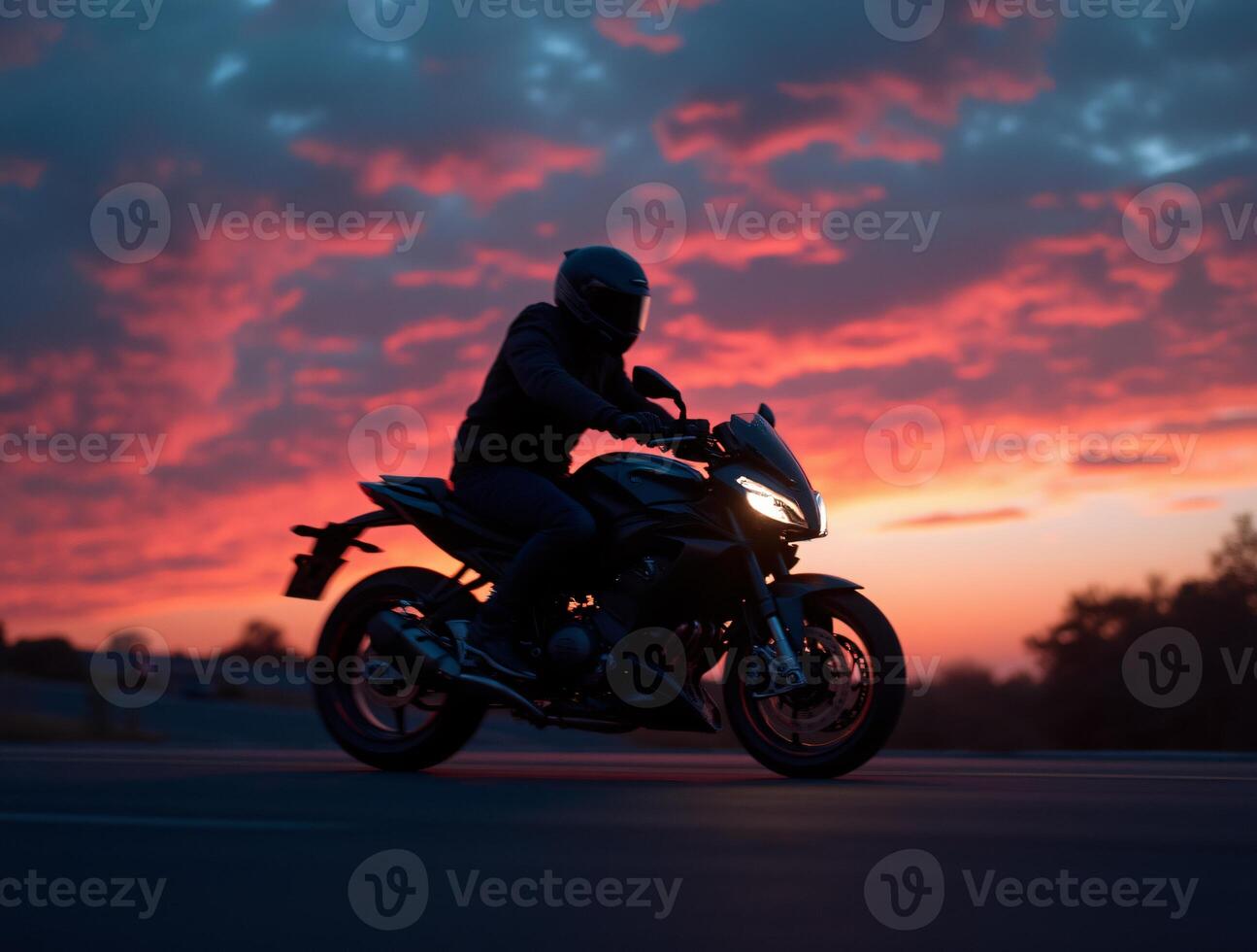 A person riding a motorcycle on a road at sunset photo