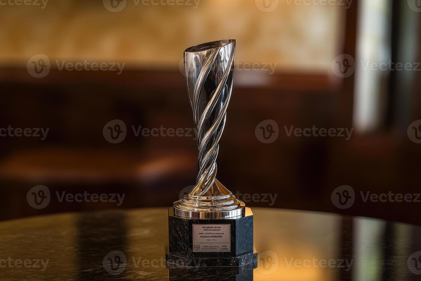 A silver trophy with a spiral design sits on a table photo