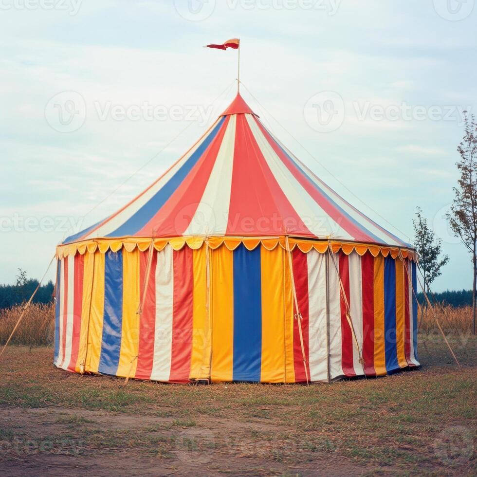 A large circus tent with a red, yellow, and blue striped canopy photo