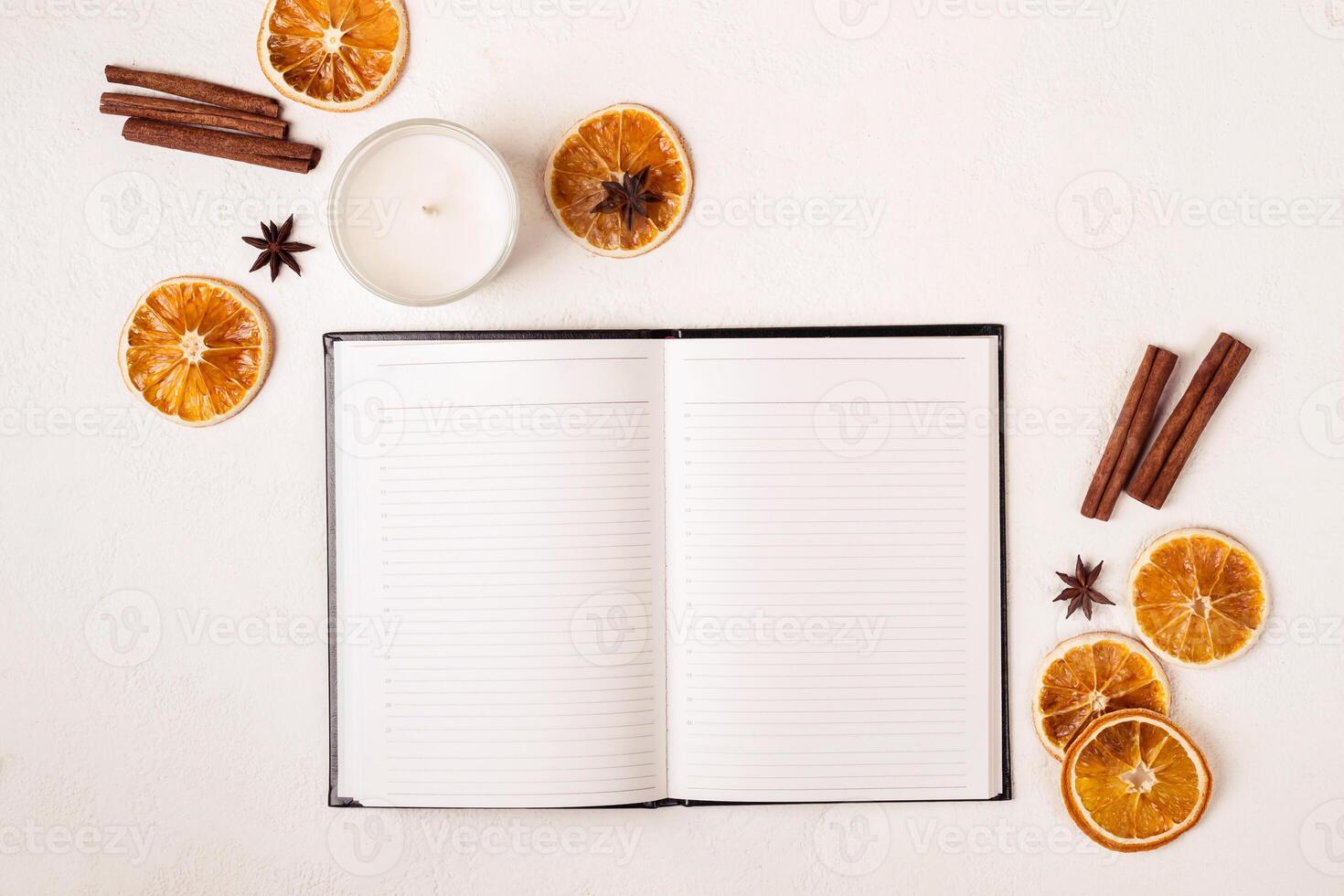 Notepad candle and autumn spices on white table photo
