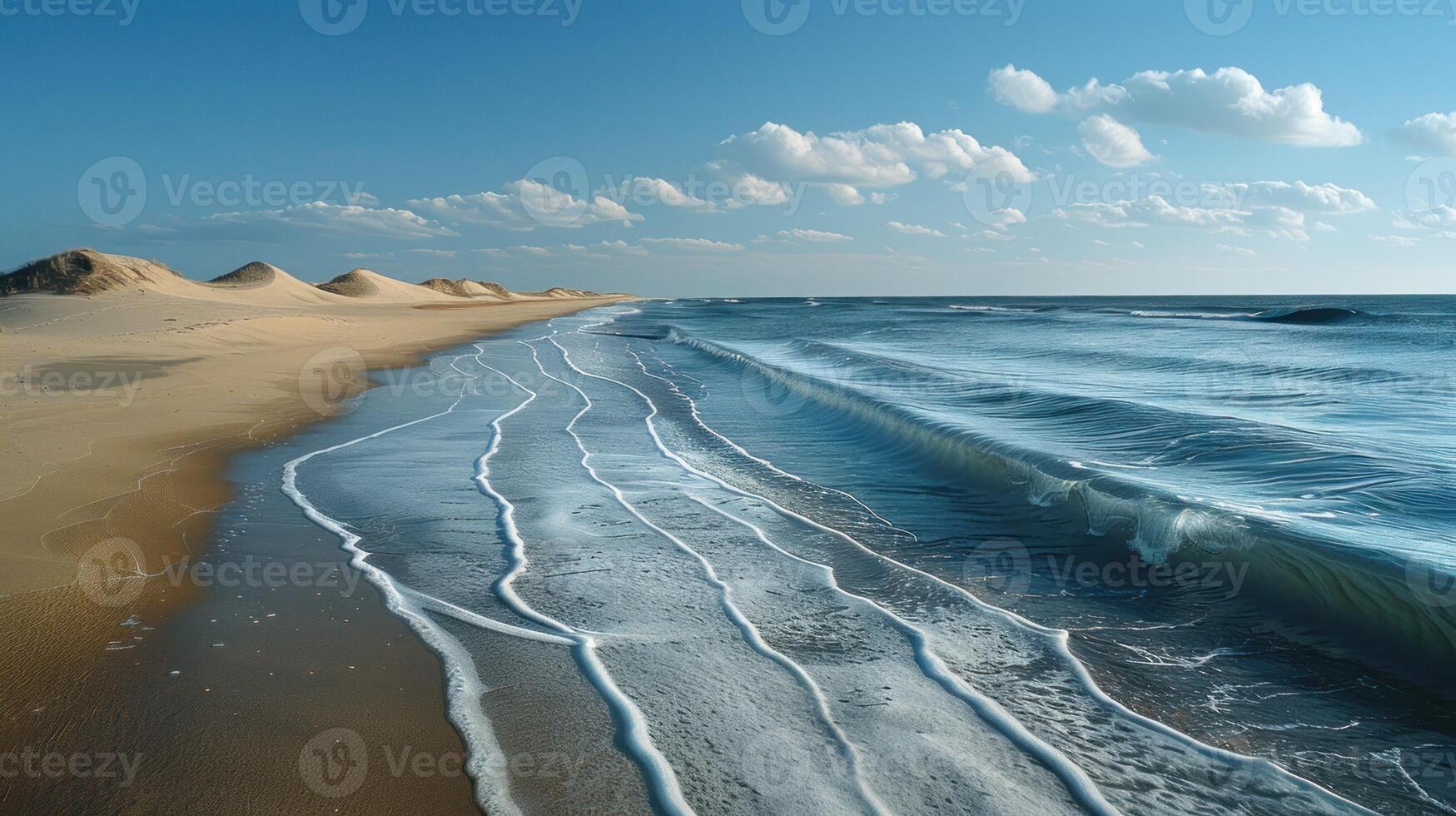 Gentle waves on a sandy beach with dunes under a clear sky. photo