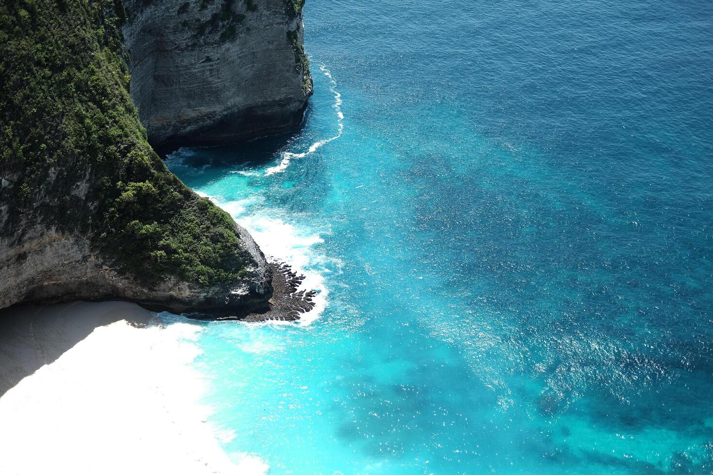 Beautiful landscape aerial view of cave of cliff rocky at the sea with foam waves and splash water of Keling king beach and ocean of Bali, Indonesia photo