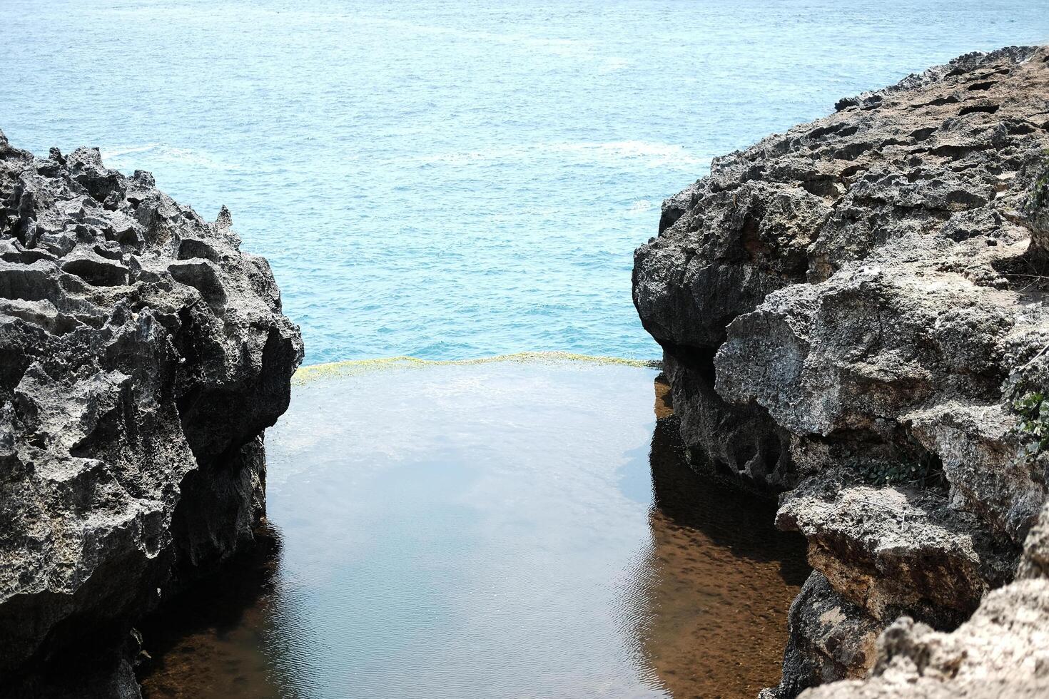 Beautiful landscape of natural pool in rocky cliff on mountain and tropical island with blue calm sea on summer for destination travel of ocean in Bali island at Indonesia photo